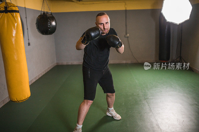 穿着运动服的男性拳击手在健身房独自训练，为拳击比赛和锦标赛做准备