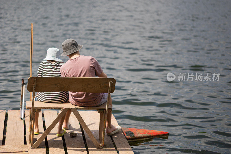 两个男孩坐在湖边的码头上