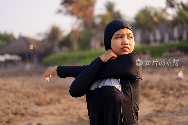 印尼穆斯林妇女穿着朴素的泳衣在海滩上伸展热身