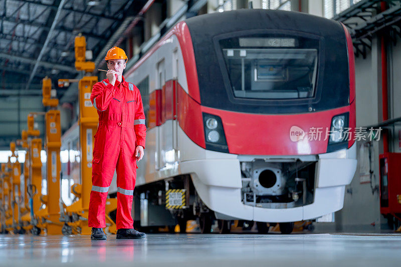 专业技术人员站在电气或地铁列车前，使用对讲机与列车工厂工作场所的团队联系。
