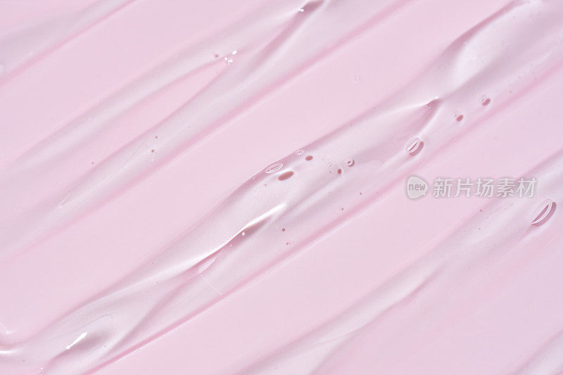 液体凝胶涂片分离在粉红色背景。美容化妆品污物，如纯透明芦荟乳液，面部啫喱精华液，洗面奶，沐浴露或洗发水