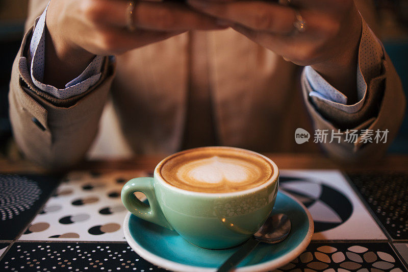 一个女人在咖啡馆里端着一杯咖啡的特写