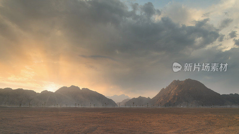 戏剧性的日落在沙漠景观与山剪影和多云的天空。风景优美的背景。