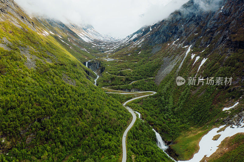 蓝色汽车在风景秀丽的绿山谷发夹路的鸟瞰图