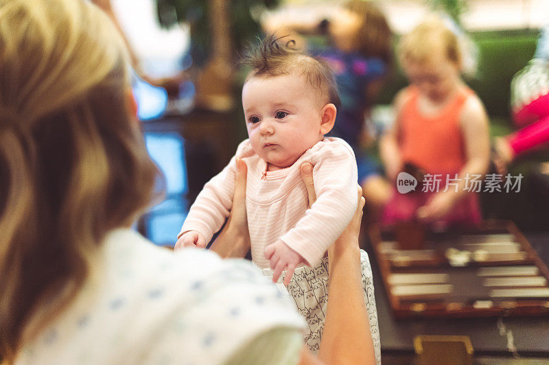 一名女子在社交聚会上抱着一个可爱的、表情丰富的小婴儿