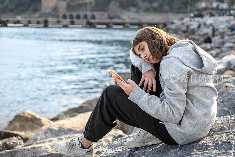 美丽的少女在海边使用手机