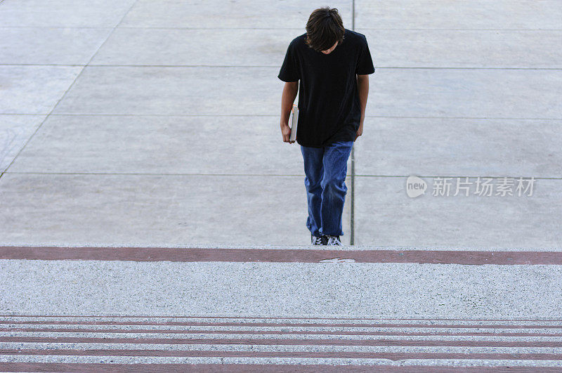一个十几岁的男孩孤独地走上学校的台阶