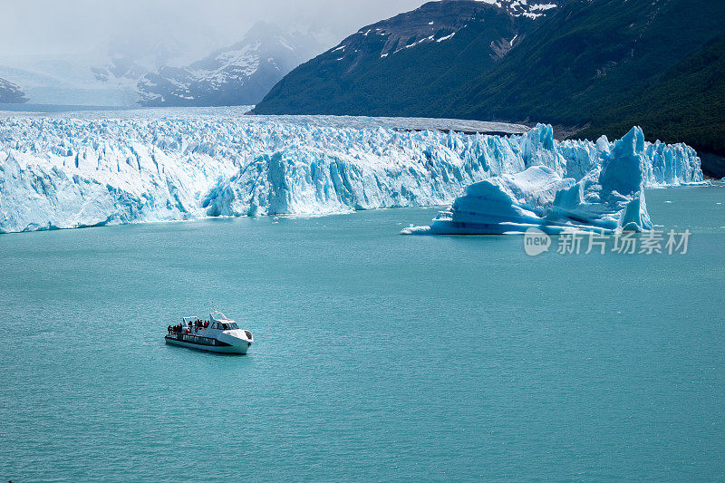 双体船在阿根廷佩里托莫雷诺冰川雄伟的冰墙前航行