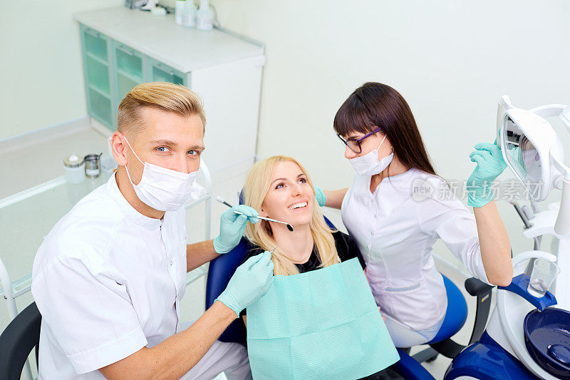牙医兼助手正在给一个女孩治疗牙齿
