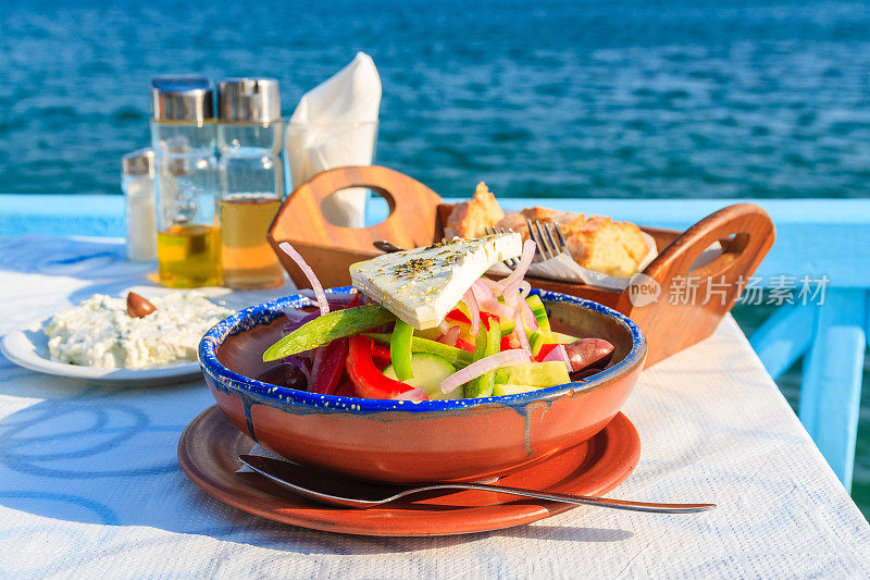 希腊萨摩斯岛，蓝色海水背景下的希腊酒馆桌上的希腊沙拉