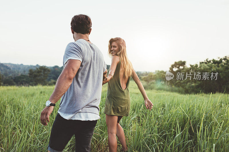 一对年轻夫妇正在草地上散步