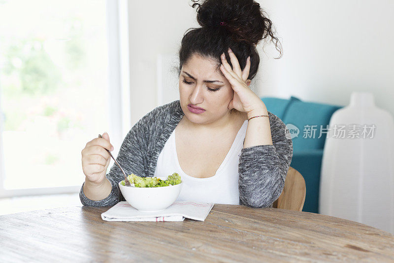 年轻的西班牙妇女饮食吃沙拉不开心