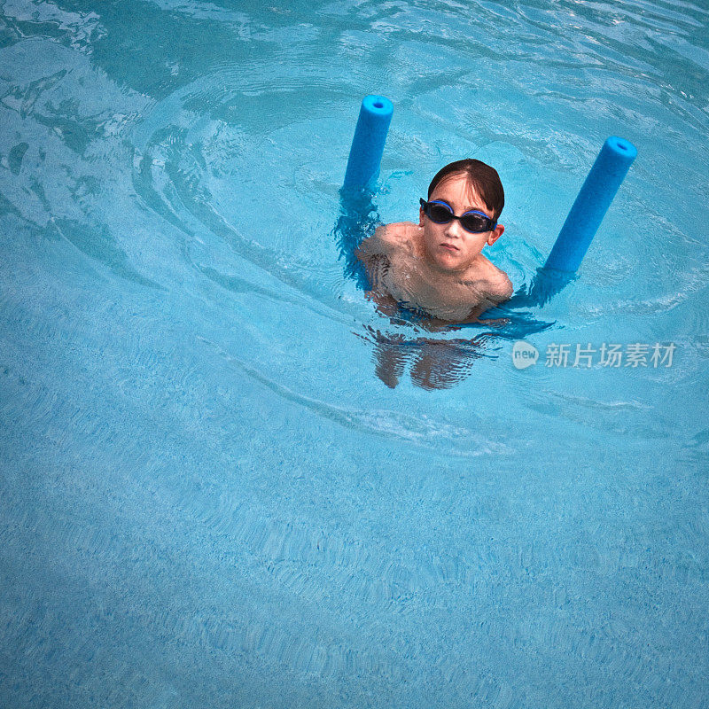一个戴着深色护目镜的小孩在游泳池里