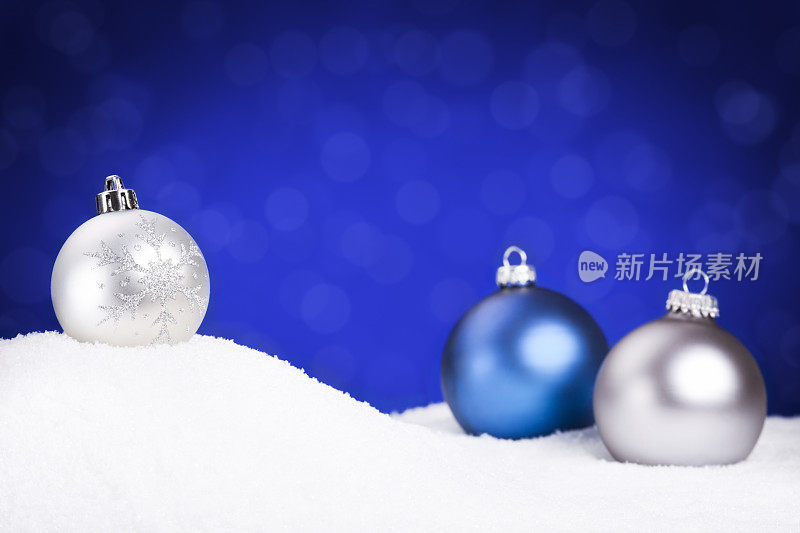 银色和蓝色的圣诞装饰物上的雪，蓝色的背景