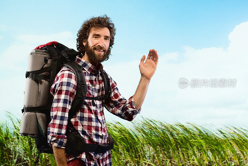 微笑的徒步旅行者看着相机和挥手