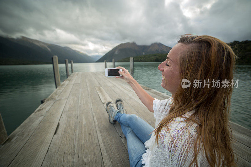 快乐的女人在湖码头上自拍