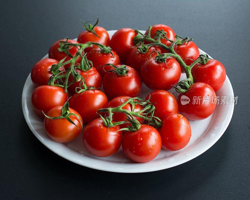 在白盘子上洗过的新鲜熟透的西红柿