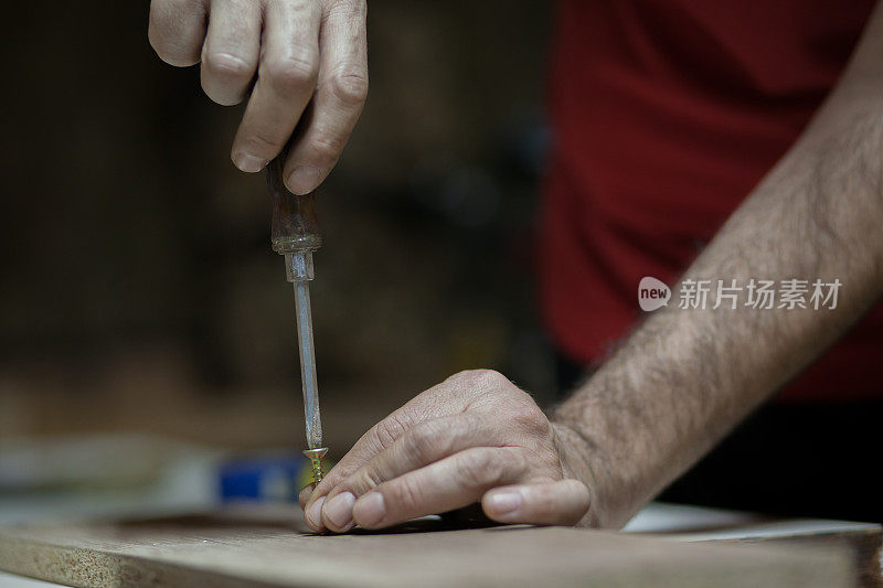 木匠用螺丝刀和螺丝把木板连接起来