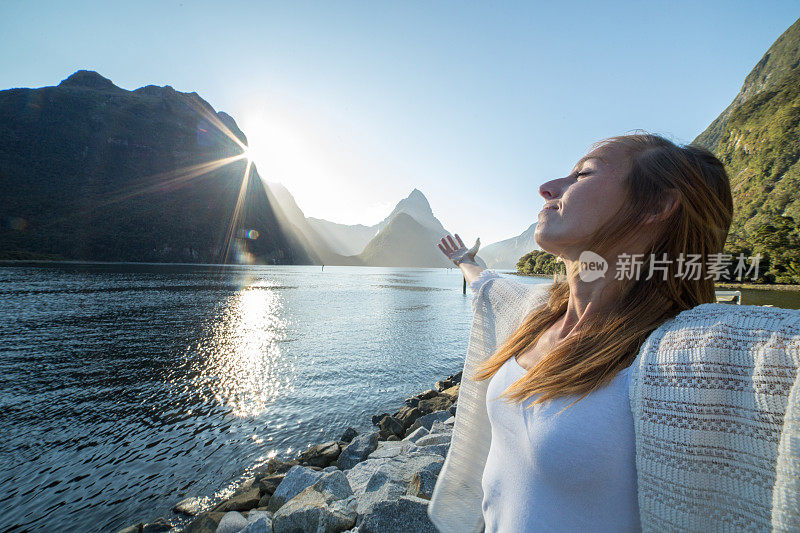 欢呼的年轻女子在山景中张开双臂