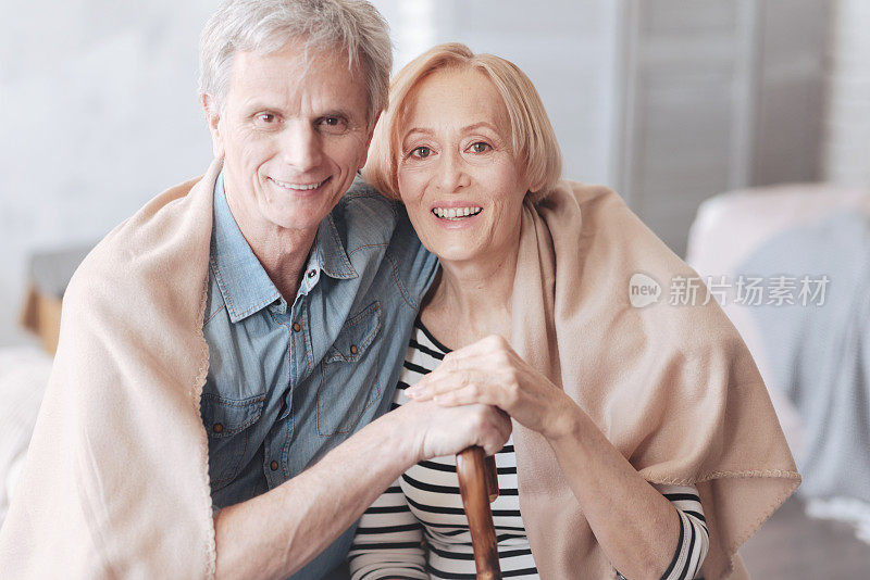 可爱的退休夫妇拥抱，对着镜头微笑