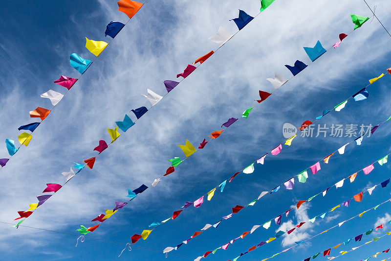 小可爱的彩旗挂在绳上，以明亮的蓝天和白云为背景，悬挂在户外。意大利撒丁岛。