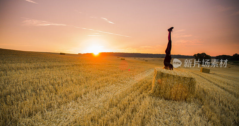 日落时分，一个女人在干草堆上倒立