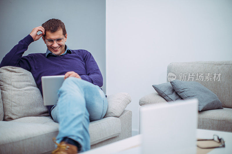商人坐在沙发上使用数码平板电脑