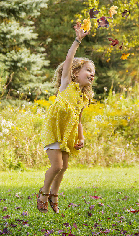 小女孩跳得很高去接掉落的树叶