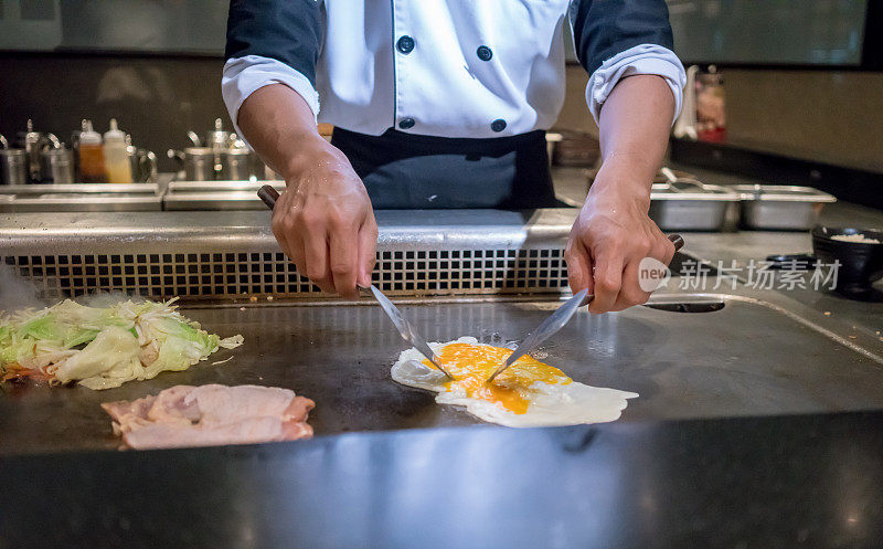 厨师手在顾客面前用热平底锅煮鸡蛋。日本Tepanyaki牛排