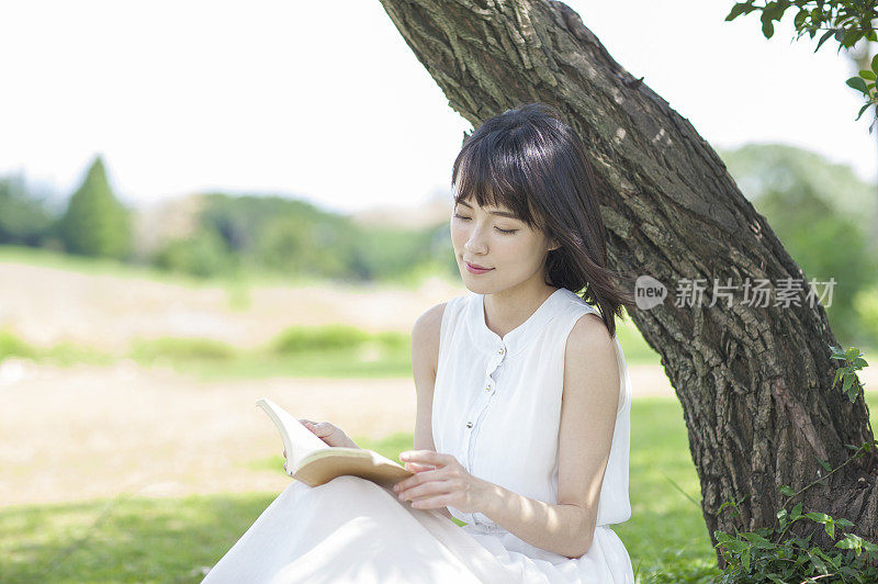 年轻女人坐在草地上看书