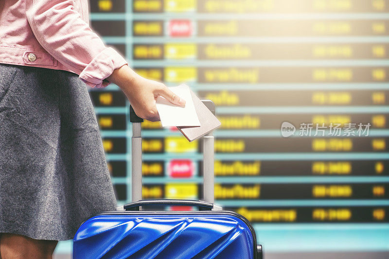 旅客妇女和行李看航班信息屏幕在机场旅游概念
