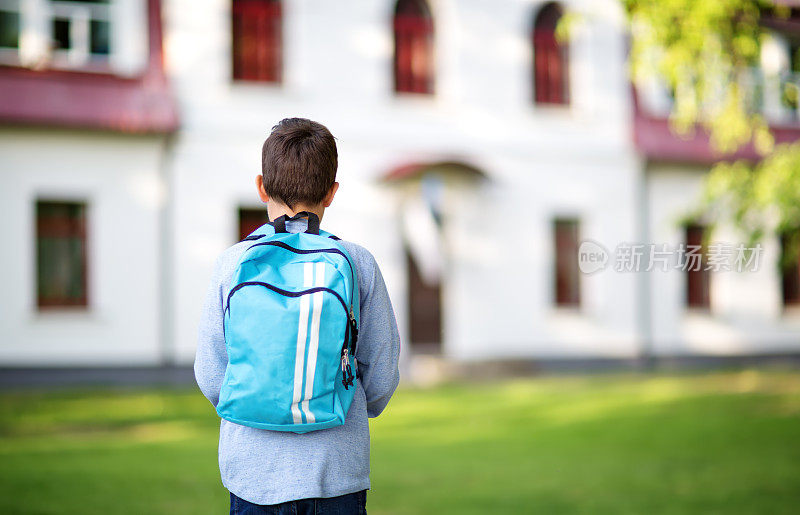 一个背着背包的男孩站在教学楼前