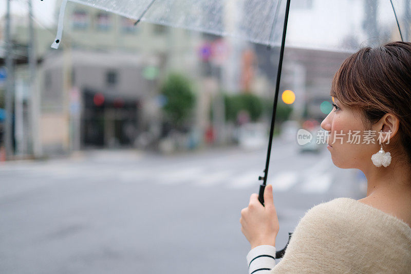 一名妇女走在东京神乐坂传统老城的街道上，在一个雨天