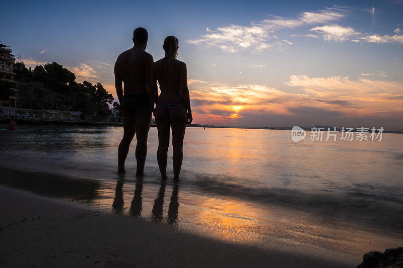 一对情侣站在马略卡岛日落时的海边
