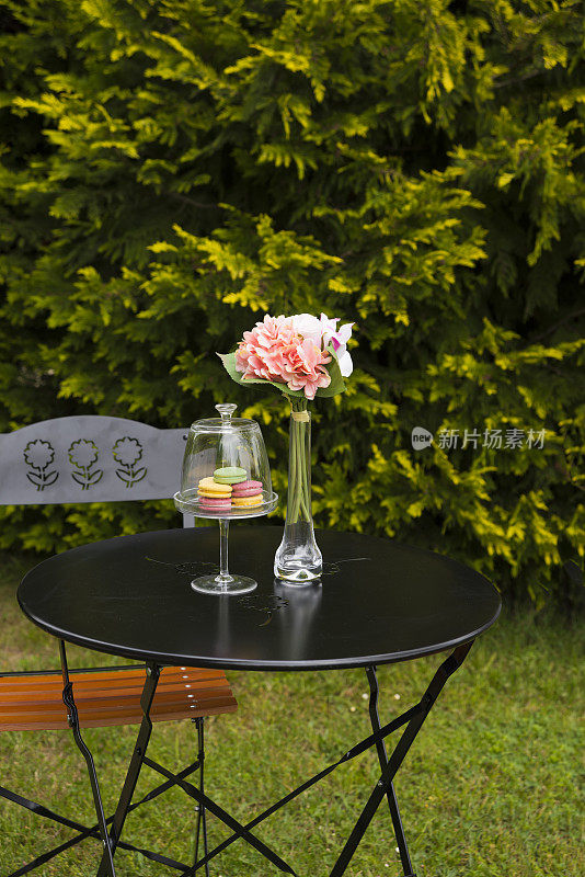 彩色的马卡龙在覆盖玻璃碗与绣球花在花园里