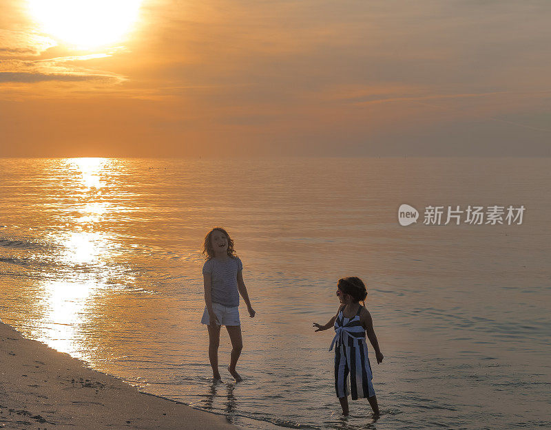 酷酷的孩子们，戴着墨镜的小女孩和一个姐妹或朋友在海边沙滩上奔跑，快乐，看起来很酷，而且充满活力