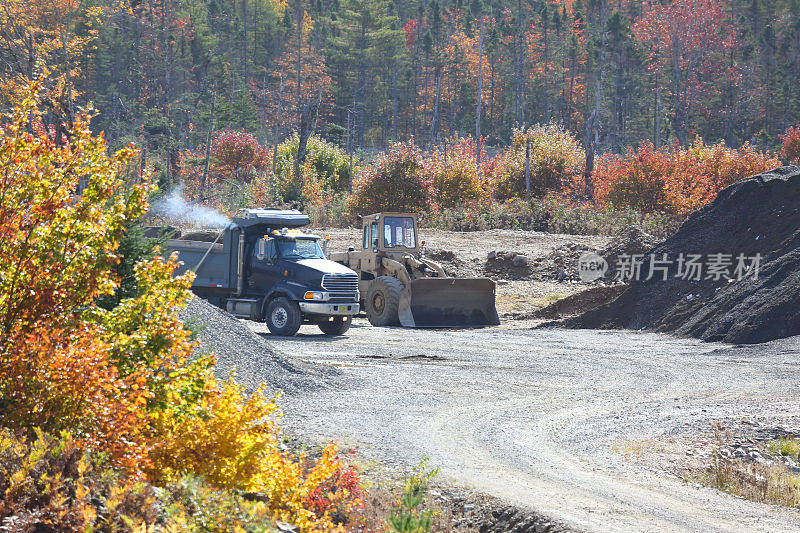 卡车和挖掘机在沙砾坑