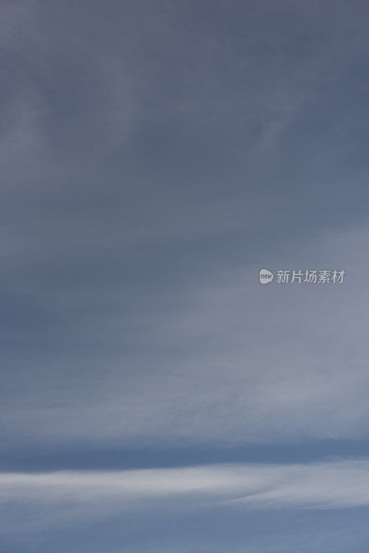 淡蓝色天空中薄的、阴云层的卷积云和高积云的垂直影像。