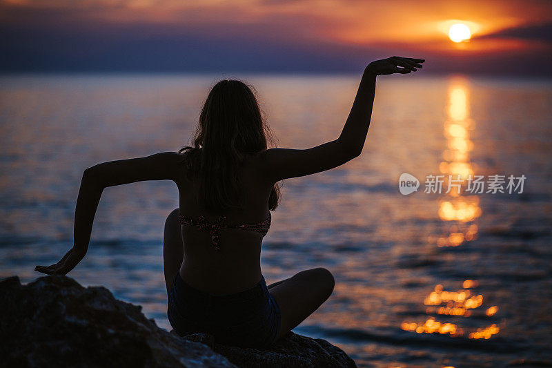 在田园诗般的夕阳下的海滩上做瑜伽