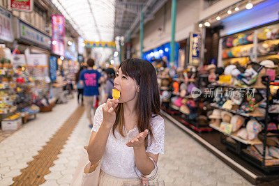 年轻女子在购物街上吃菠萝