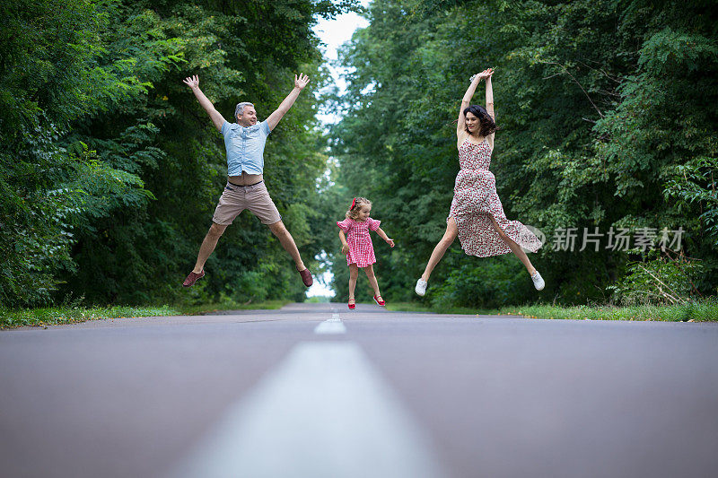 欢乐的一家人在乡间小路上跳跃。
