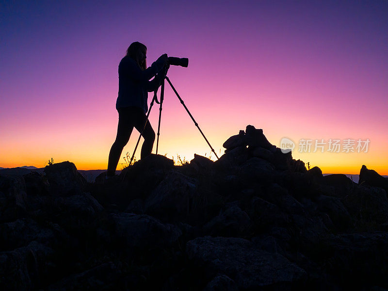 女摄影师剪影日落山顶