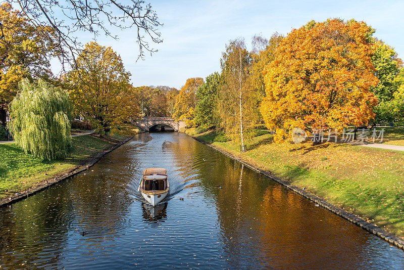 秋天，一条游船穿过北欧城市中心的河流