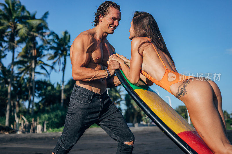 冲浪者和他美丽的女朋友在海滩上玩