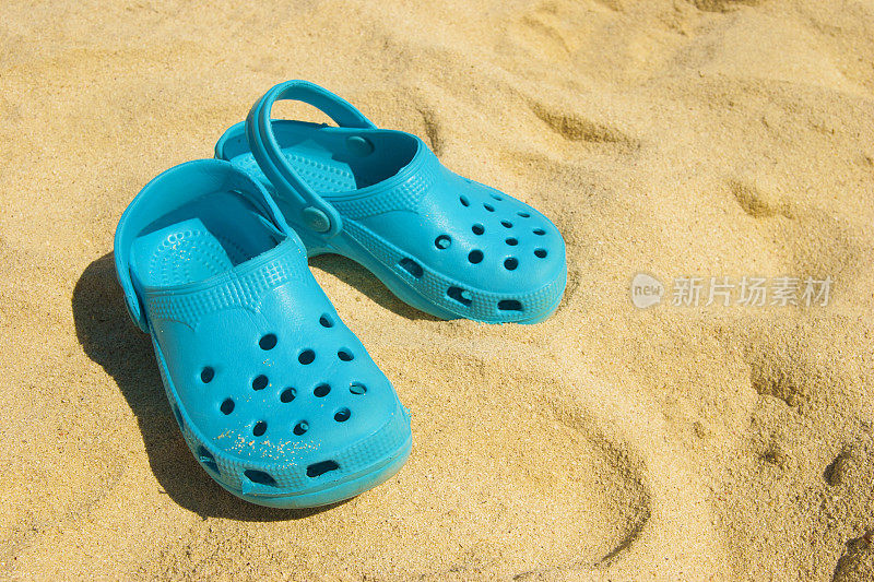海边度假:在沙滩上穿着休闲的蓝色木屐鞋