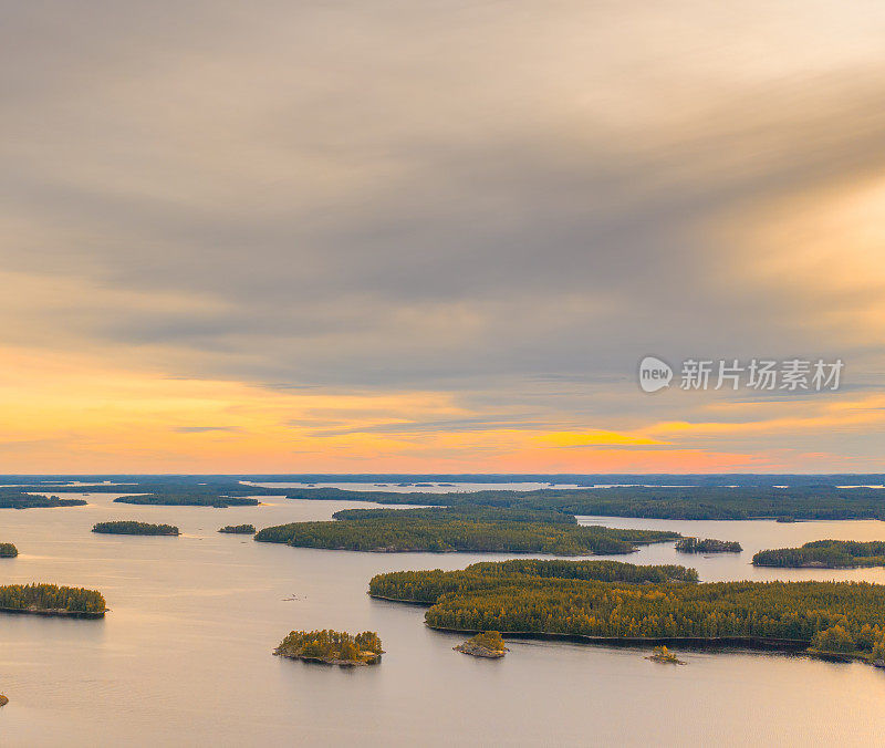鸟瞰图上的小岛上蓝色的湖Saimaa。景观与无人机。在多云的夏日日落上，可以俯瞰蓝色的湖泊、岛屿和绿色的森林。芬兰的湖泊景观。