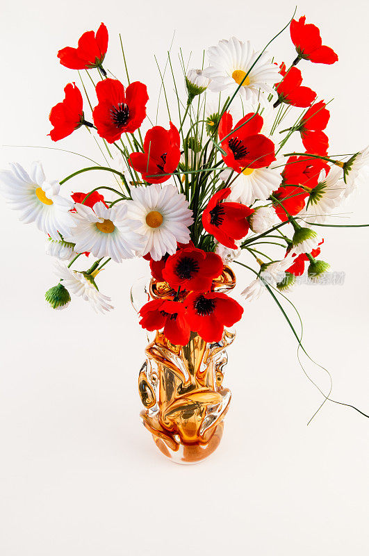 花瓶与人造的红色罂粟和白色洋甘菊。