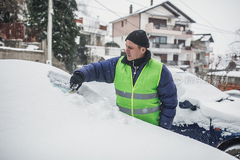 一位老人正在清除车上的积雪