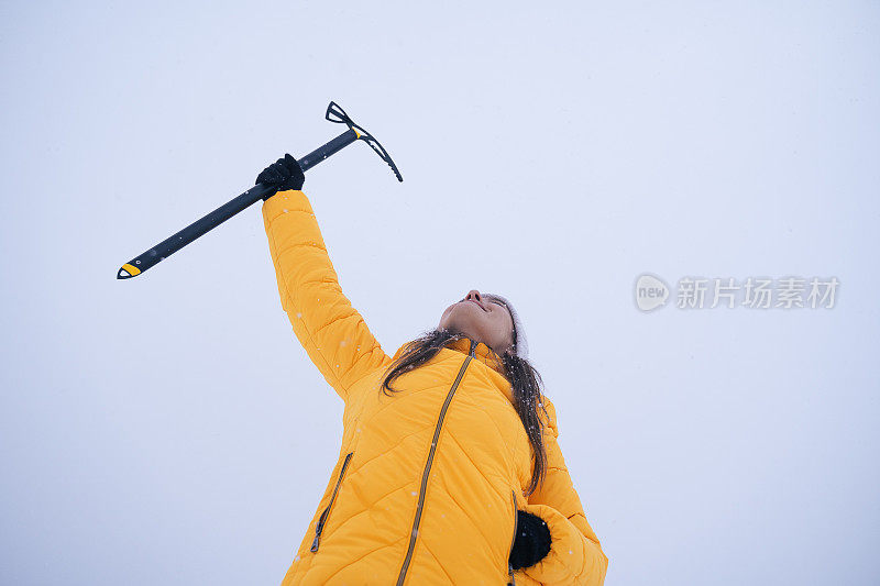 带着冰锥的冬季旅行家。年轻的女游客走在深深的雪中，享受冬天的山。肖像。