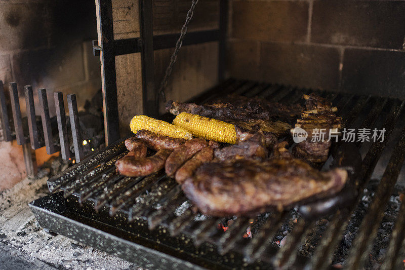 各种煮熟的肉、香肠和玉米棒放在烧烤架上